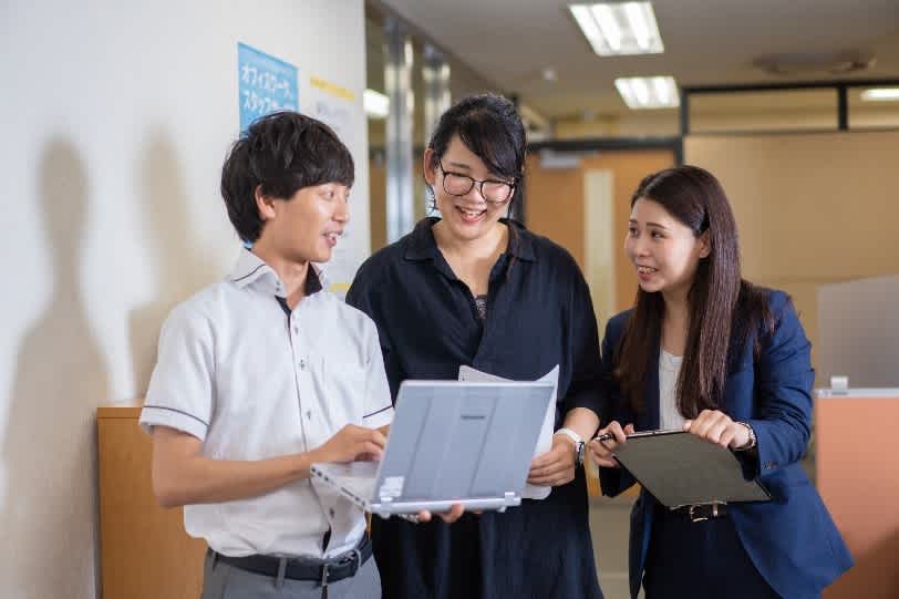 Employees standing and talking with a laptop