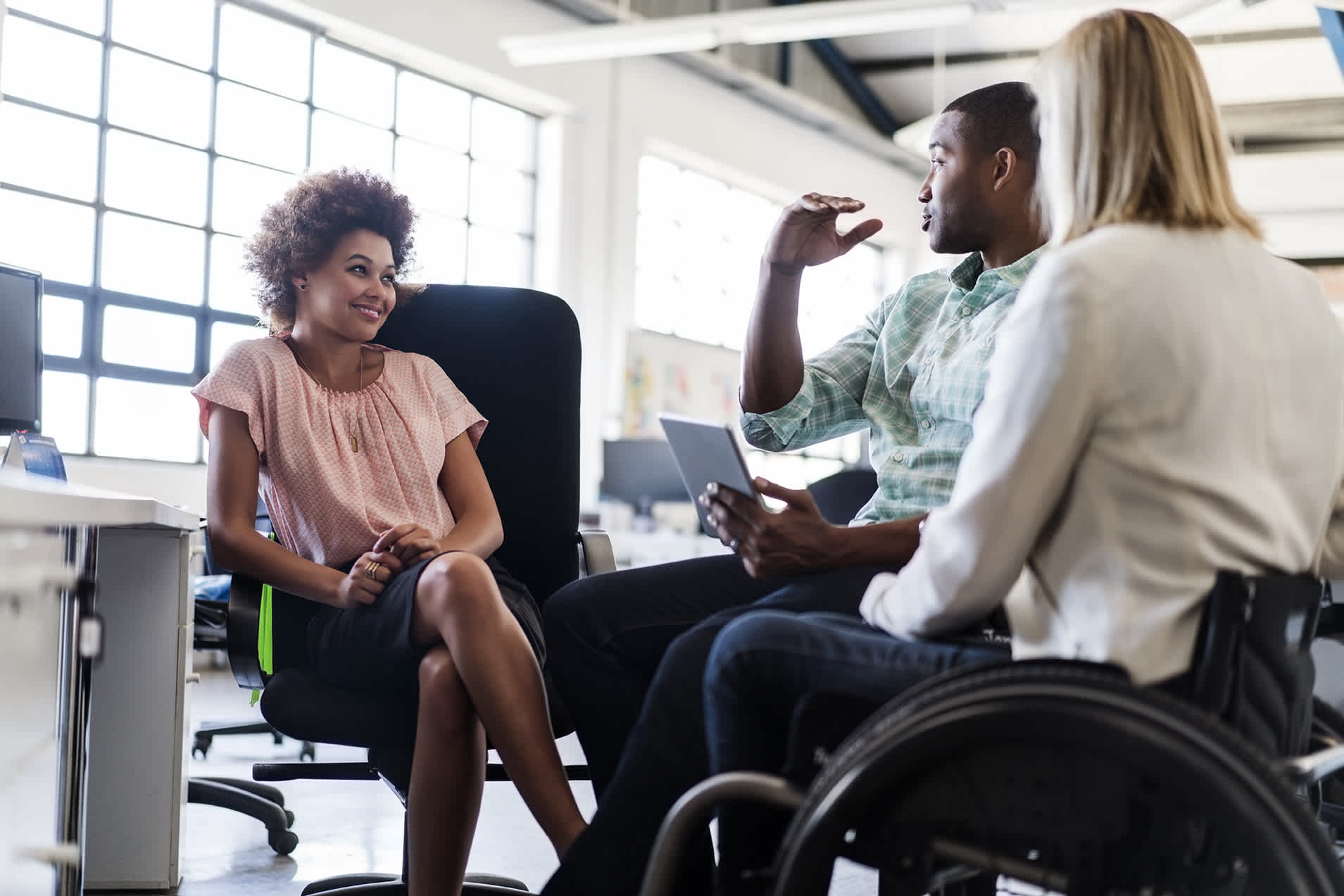 An image of three colleagues having a conversation in the office